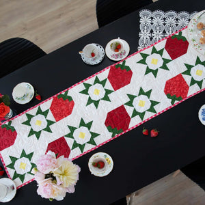 Favorite Things Precut Table Runner Bundle quilt kit; red, green and white patchwork with pink border.