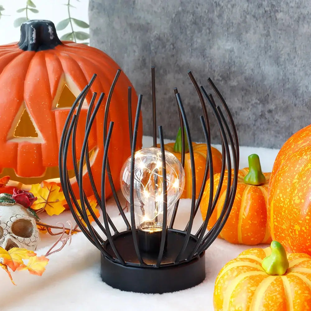 7-inch tall battery-powered table lamp with black metal wire-frame globe surrounding a clear bulb.
