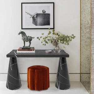 Toros black marble console with cone-shaped legs; decor includes horse statue, books, vase, and orange ottoman.
