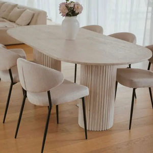 Troia Light Travertine Oval Dining Table with fluted pedestal legs, beige chairs.