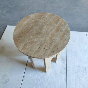 Round travertine end table with honed surface and light wood U-shaped legs, 18 in diameter, 20 in high