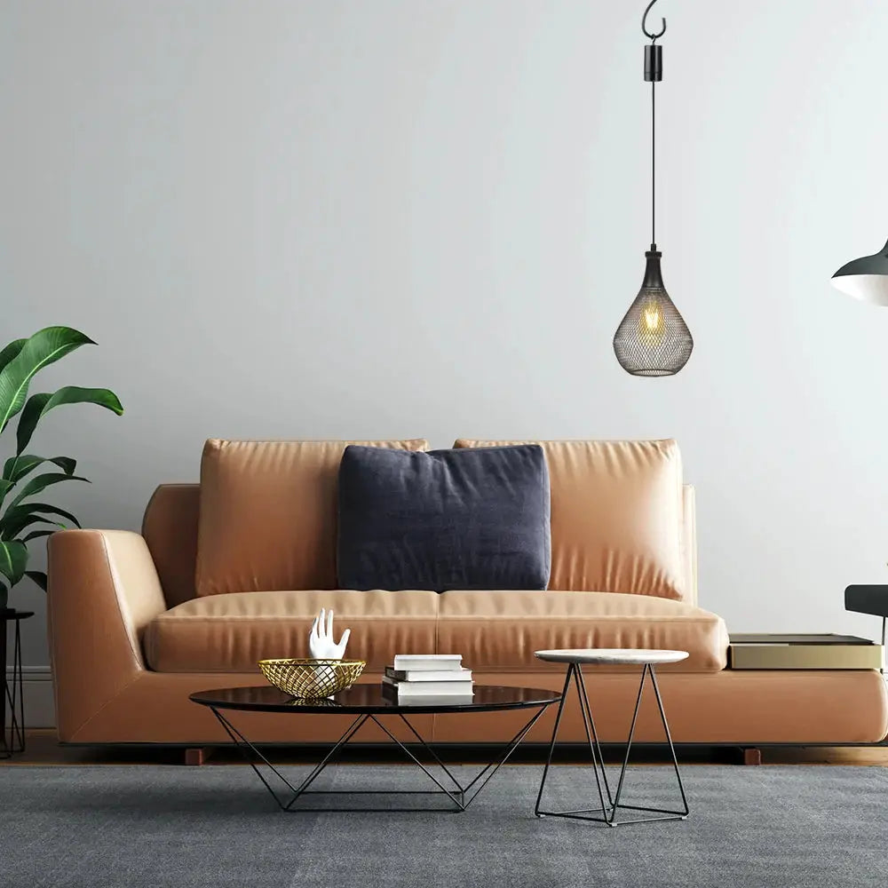 Set of 2 hanging lamps, battery-operated teardrop cage pendants in dark metal over a living room sofa.