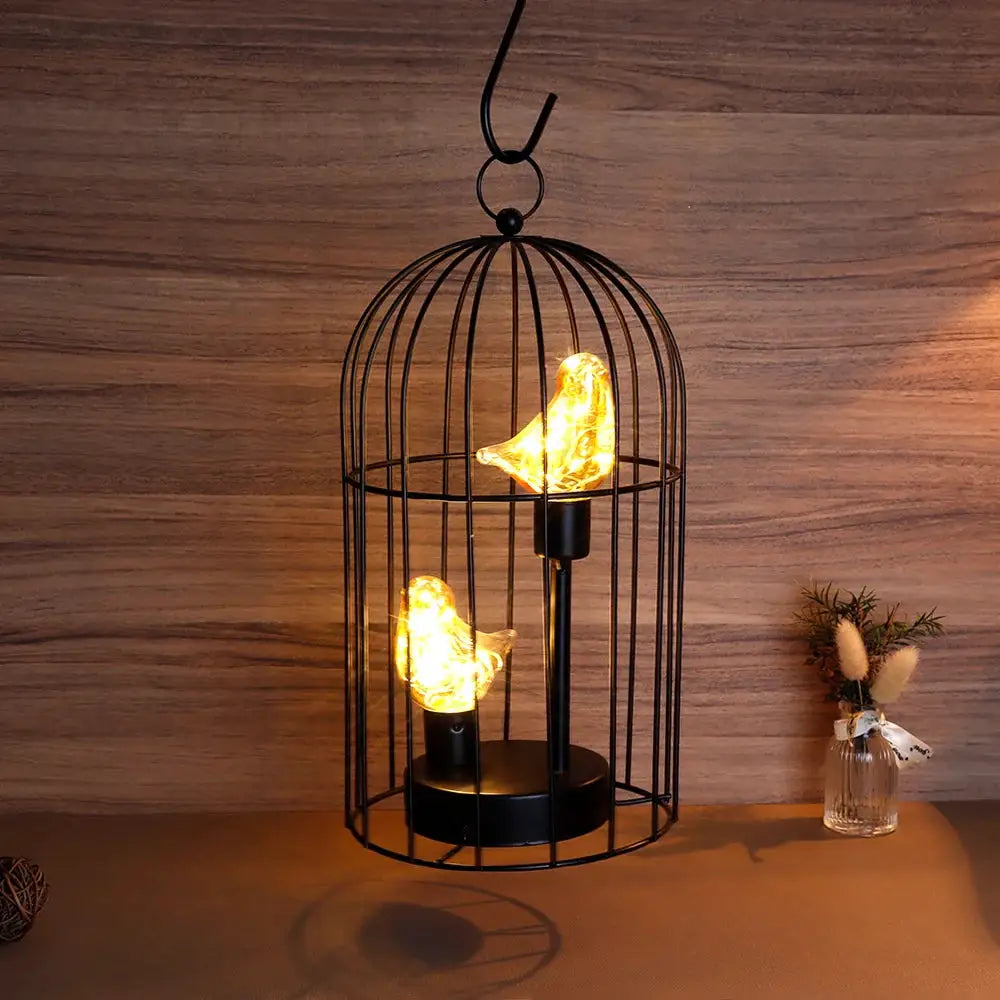 12-inch tall battery-operated birdcage lamp with warm amber bird-shaped LEDs inside a black metal cage