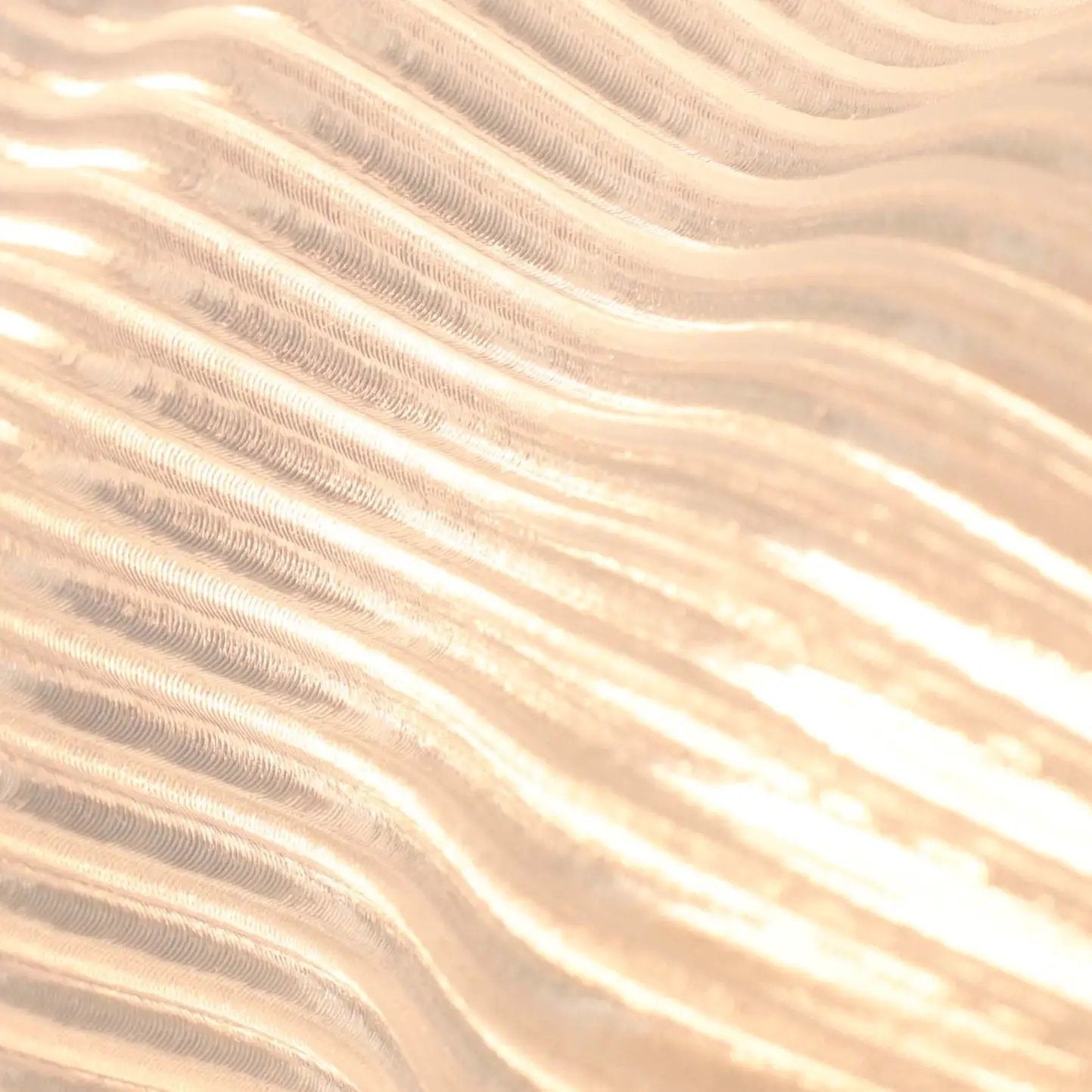 Yuji table lamp by Terra Labs, peach-gold brushed metal finish with wave-like ridges.
